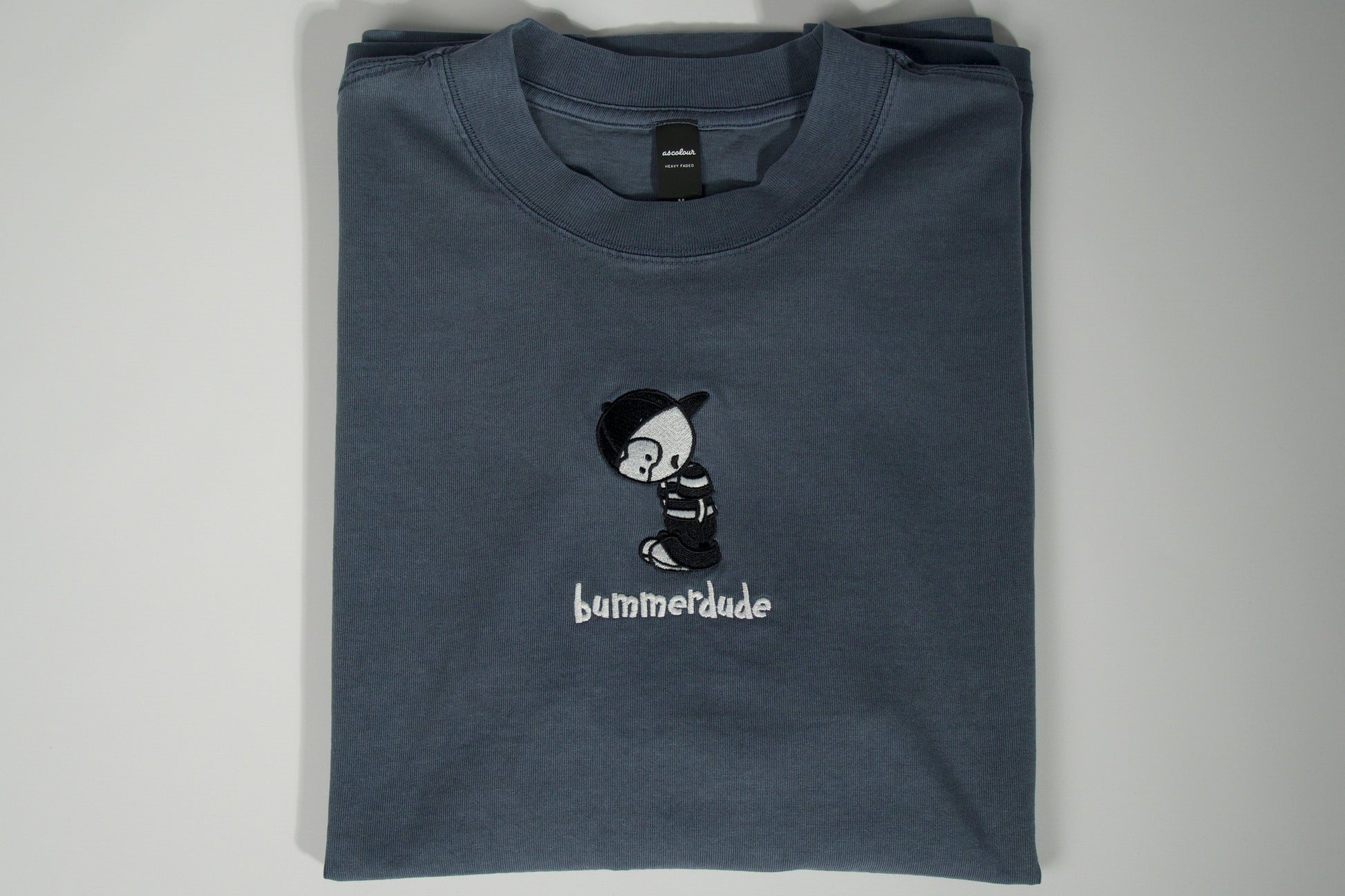 Folded blue t-shirt with a graphic design and text on a gray background